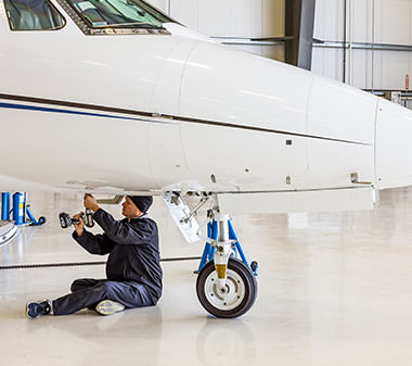 a mechanic working on the underside of a small jet