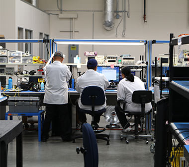 three people in lab coats working around a computer workstation