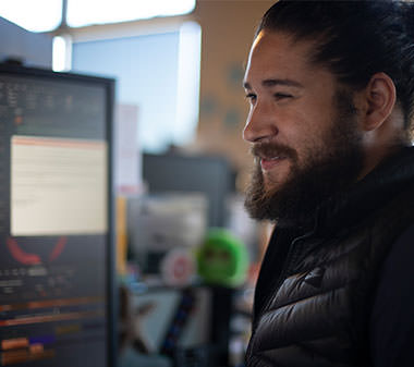 a man with a beard smiling while working at the computer