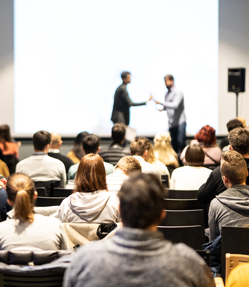 Crowd looks on to a presentation on stage
