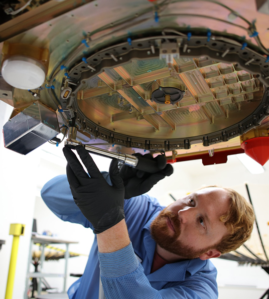 An engineer works on a satellite