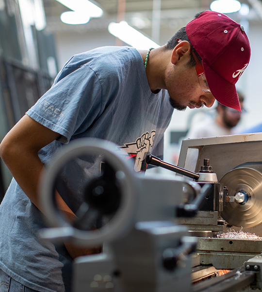 A student working at a piece of machining equipment