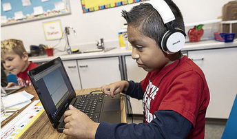 boy with headphones at a computer in a classroom