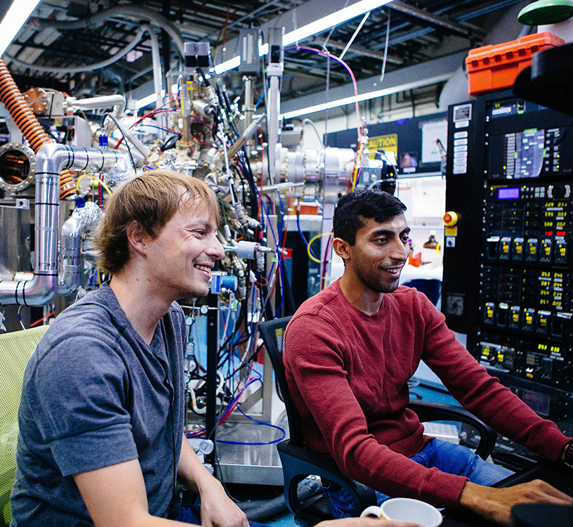 two students surrounded by photonics equipment